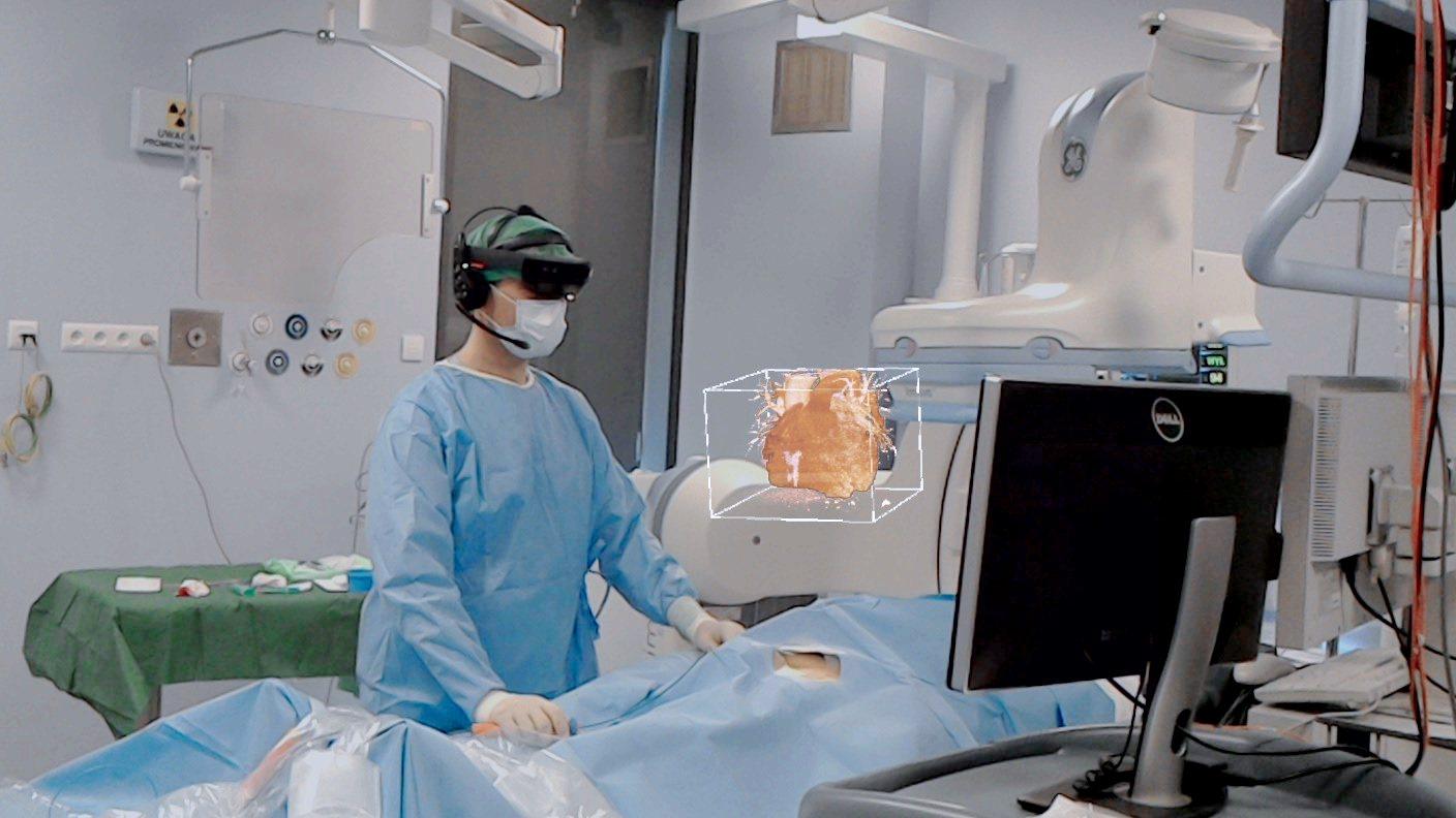 Physician in a HoloLens headset viewing a holographic heart model at the procedure table